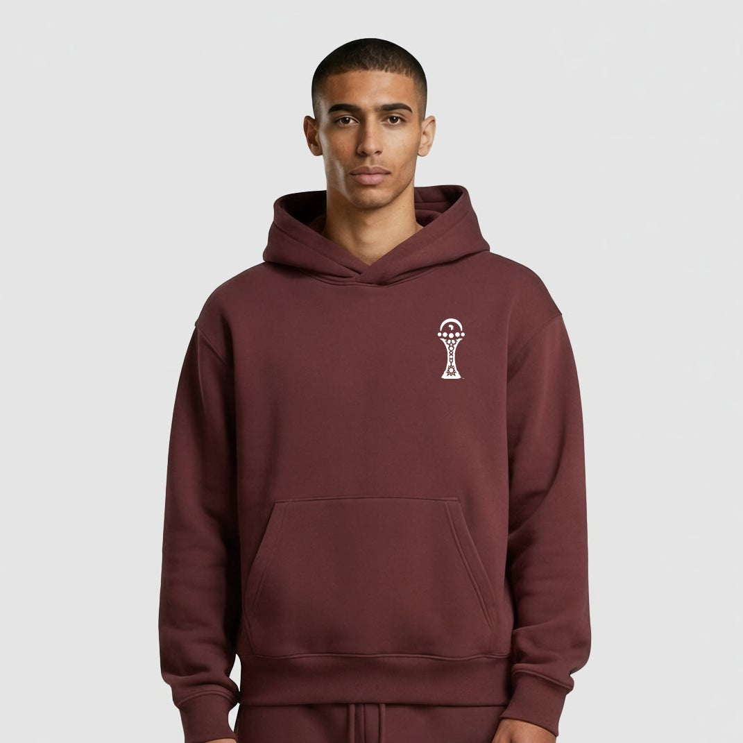 Man wearing a maroon hoodie with a small logo on a light gray background